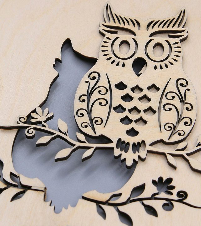 Close-up of a carved wooden owl with intricate patterns on a branch.